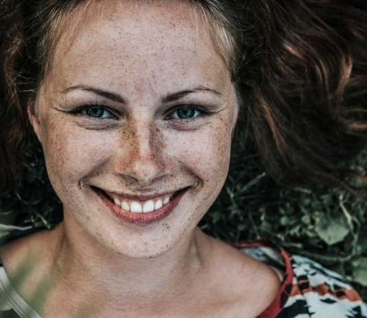 Alcanzar la felicidad con 3 ejercicios simples Mujer echada en un campo y feliz